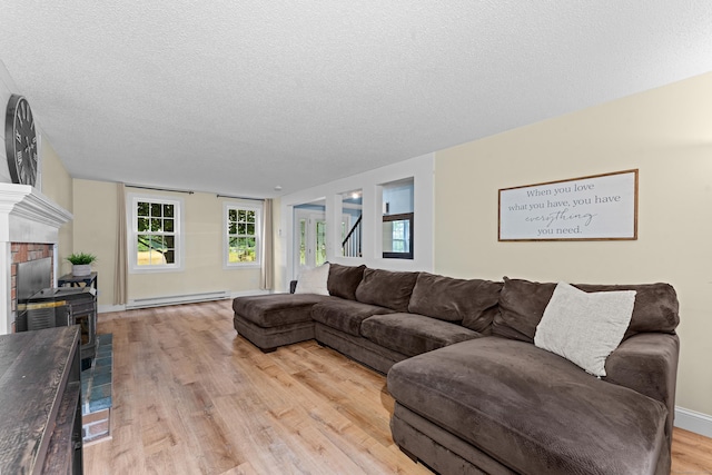 148 Depot St, East Windsor, CT 06016 - living room featuring baseboard heating, a textured ceiling, light wood-type flooring, and a fireplace