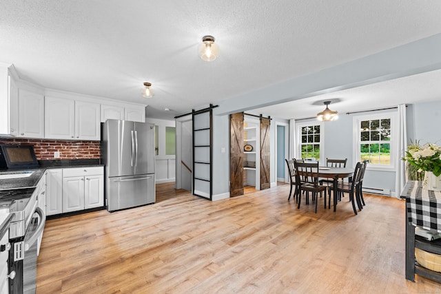 148 Depot St, East Windsor, CT 06016 - kitchen with freestanding refrigerator, a barn door, dark countertops, white cabinets, and a textured ceiling