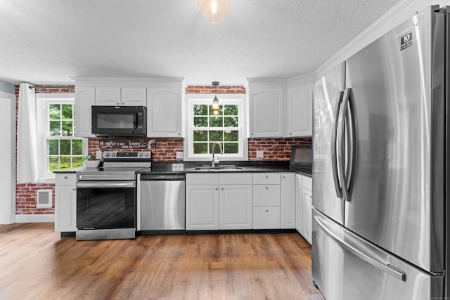 148 Depot St, East Windsor, CT 06016 - kitchen with appliances with stainless steel finishes, dark countertops, a textured ceiling, white cabinetry, and wood finished floors