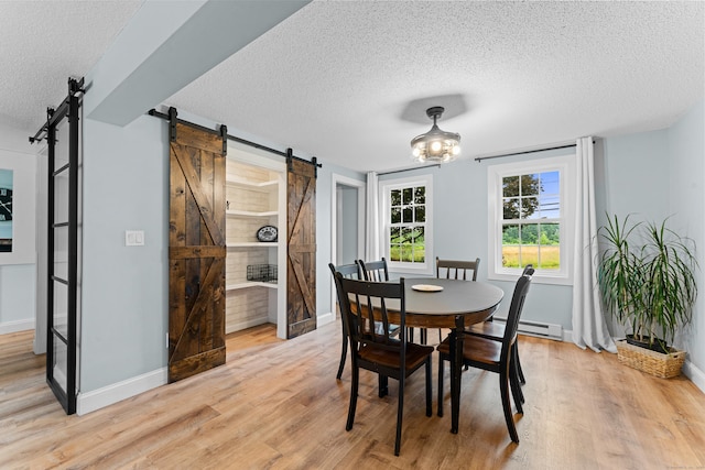 148 Depot St, East Windsor, CT 06016 - dining space featuring a barn door, a textured ceiling, light wood-type flooring, and a baseboard radiator