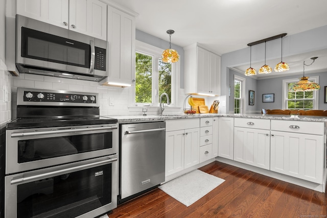 50 Spring Glen Dr, Granby, CT 06035 - kitchen with stainless steel appliances, dark wood-type flooring, decorative backsplash, a peninsula, and healthy amount of natural light