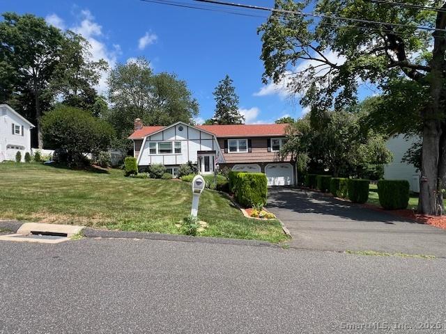 38 Pine St, Trumbull, CT 06611 - raised ranch featuring driveway, a front yard, a chimney, and an attached garage