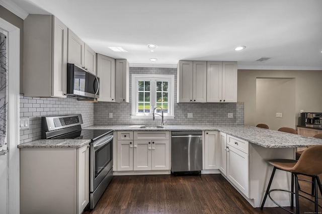 18 Holly Ln, Wallingford, CT 06492 - kitchen with appliances with stainless steel finishes, a peninsula, a breakfast bar, dark wood-style floors, and tasteful backsplash