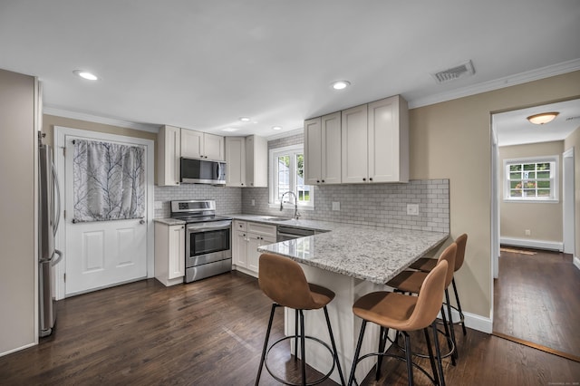 18 Holly Ln, Wallingford, CT 06492 - kitchen featuring appliances with stainless steel finishes, a peninsula, light stone countertops, crown molding, and backsplash