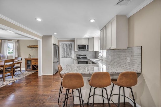 18 Holly Ln, Wallingford, CT 06492 - kitchen featuring stainless steel appliances, ornamental molding, a peninsula, backsplash, and light stone countertops