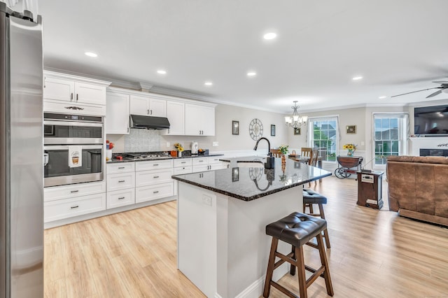 54 Pondview Cir Unit 54, Beacon Falls, CT 06403 - kitchen with appliances with stainless steel finishes, under cabinet range hood, ornamental molding, open floor plan, and a kitchen breakfast bar