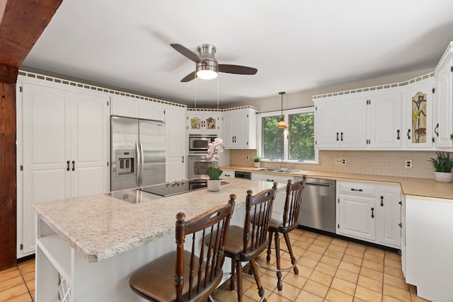 84 Kanungum Trl, Shelton, CT 06484 - kitchen featuring stainless steel appliances, a kitchen island, tasteful backsplash, a ceiling fan, and white cabinetry