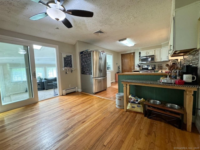 860 Suffield St, Suffield, CT 06078 - kitchen featuring appliances with stainless steel finishes, baseboard heating, light wood finished floors, a textured ceiling, and ceiling fan