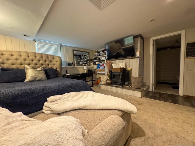 860 Suffield St, Suffield, CT 06078 - carpeted bedroom featuring a wood stove, wood finished floors, and wooden walls
