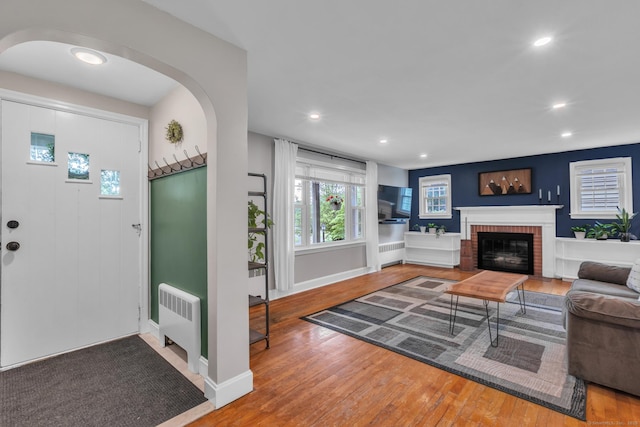 140 Ridgewood Rd, East Hartford, CT 06118 - living room featuring radiator, wood finished floors, recessed lighting, arched walkways, and a fireplace