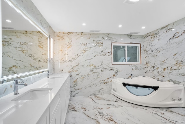 45 Hunting Ridge Rd, Easton, CT 06612 - bathroom featuring a garden tub, stone wall, double vanity, recessed lighting, and marble tiled floors