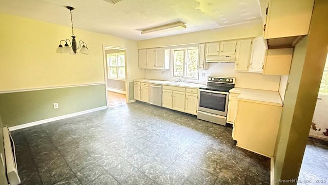 kitchen with stainless steel appliances, under cabinet range hood, a chandelier, light countertops, and decorative light fixtures