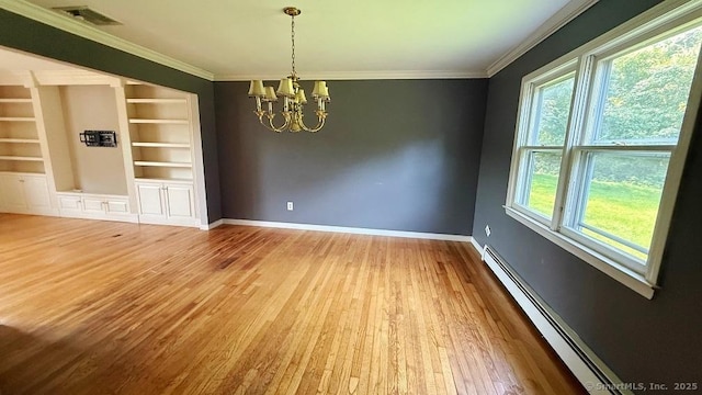 empty room featuring a baseboard heating unit, a chandelier, wood finished floors, crown molding, and built in shelves