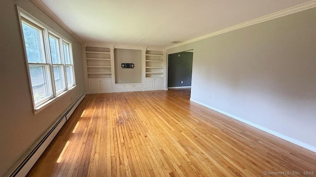 empty room featuring a baseboard heating unit, built in shelves, light wood-style floors, and ornamental molding