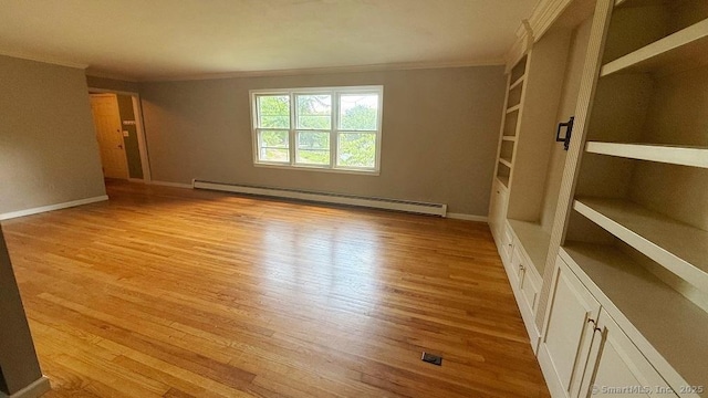 empty room with a baseboard heating unit, crown molding, light wood-type flooring, and built in features