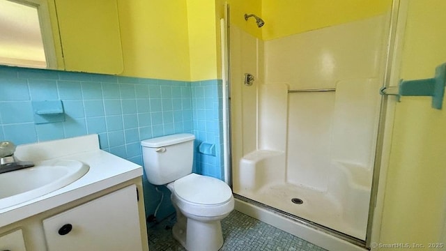 full bathroom with a walk in shower, vanity, wainscoting, tile walls, and tile patterned floors