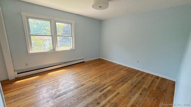 empty room featuring baseboard heating and wood finished floors