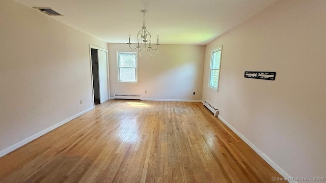 spare room featuring baseboard heating, a chandelier, a baseboard radiator, and light wood finished floors