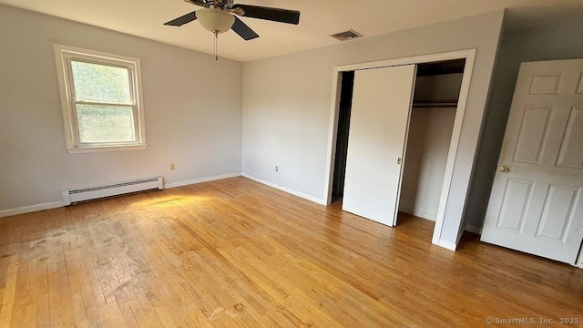 unfurnished bedroom with a baseboard heating unit, light wood-style floors, a closet, and a ceiling fan