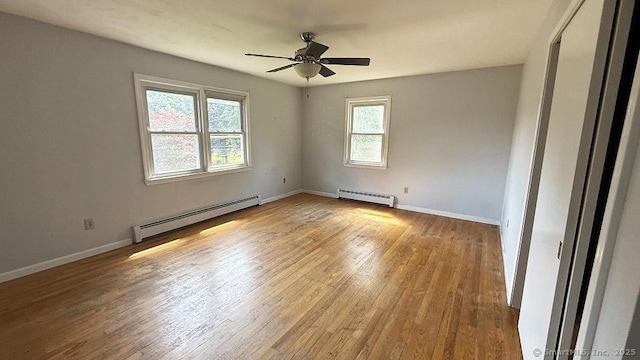 empty room featuring a baseboard radiator, a ceiling fan, and wood finished floors