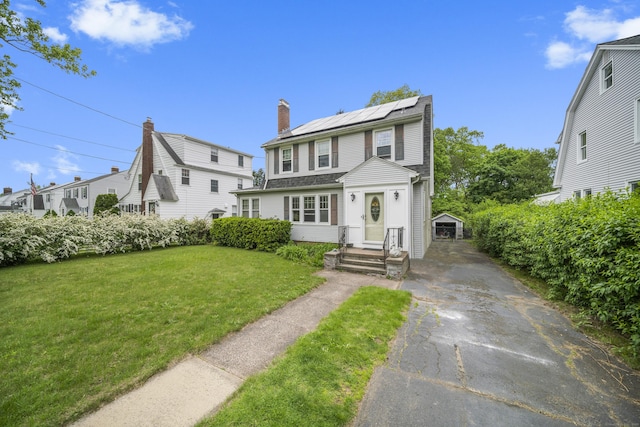 114 Kneeland Rd, New Haven, CT 06512 - view of front of property with asphalt driveway, solar panels, a front lawn, a chimney, and an outdoor structure