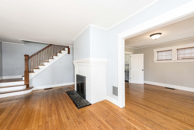 38 Francis Ave, Hamden, CT 06517 - unfurnished living room with ornamental molding, a brick fireplace, wood-type flooring, and stairway