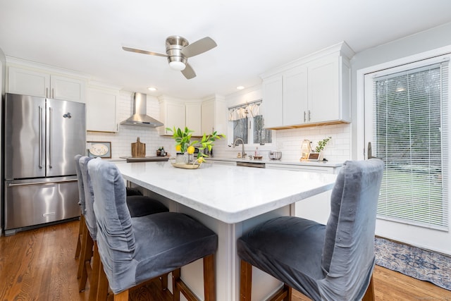 438 Woodland St, Glastonbury, CT 06073 - kitchen with high quality fridge, wall chimney range hood, a ceiling fan, a kitchen island, and light countertops