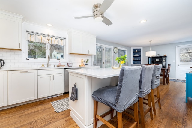 438 Woodland St, Glastonbury, CT 06073 - kitchen featuring stainless steel dishwasher, a breakfast bar area, light wood finished floors, light countertops, and tasteful backsplash