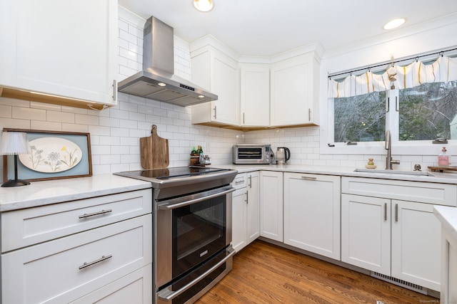 438 Woodland St, Glastonbury, CT 06073 - kitchen with electric range, wall chimney range hood, white cabinets, tasteful backsplash, and light wood finished floors