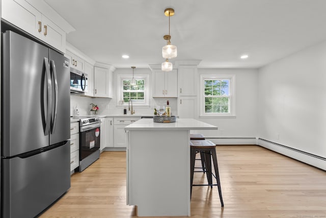 103 Perry Rd, Bristol, CT 06010 - kitchen with appliances with stainless steel finishes, a kitchen breakfast bar, light wood-type flooring, white cabinetry, and light countertops