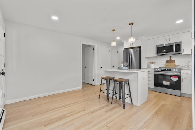 103 Perry Rd, Bristol, CT 06010 - kitchen featuring appliances with stainless steel finishes, a breakfast bar, light wood finished floors, backsplash, and recessed lighting