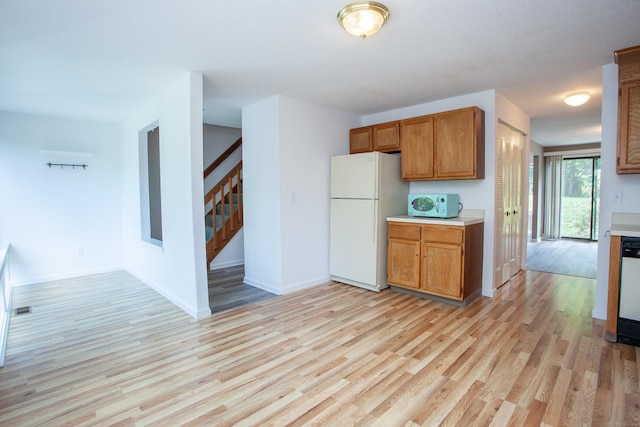 14 Old Mill Ct Unit 14, Simsbury, CT 06070 - kitchen featuring freestanding refrigerator, light countertops, light wood-style floors, and brown cabinetry