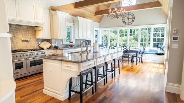 7 Taunton Ln, Newtown, CT 06470 - kitchen featuring double oven range, a breakfast bar, decorative backsplash, a chandelier, and light wood-style flooring
