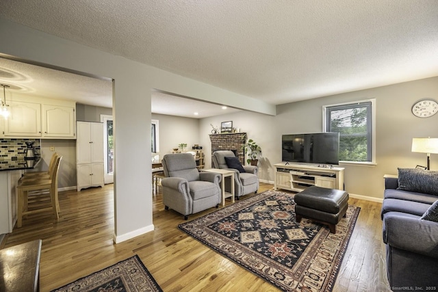 1018 Long Hill Rd, Middletown, CT 06457 - living room with light wood-style floors, a textured ceiling, a brick fireplace, and recessed lighting