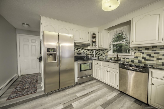 1018 Long Hill Rd, Middletown, CT 06457 - kitchen featuring appliances with stainless steel finishes, a baseboard radiator, under cabinet range hood, light wood-type flooring, and decorative backsplash