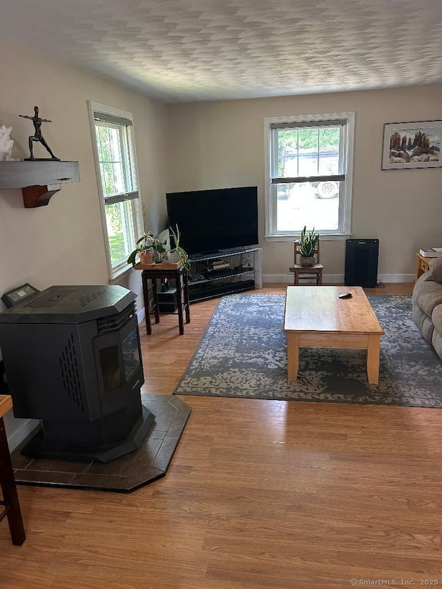 330 Dogburn Ln, Orange, CT 06477 - living area featuring plenty of natural light, a wood stove, and wood finished floors