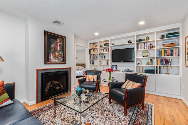 132 Deerwood Rd, Tolland, CT 06084 - sitting room with wood finished floors, a fireplace, a textured ceiling, and recessed lighting