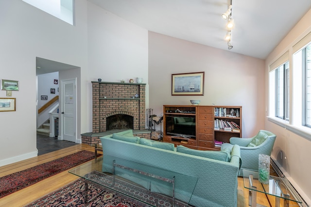109 Old Farms Rd Unit 109, Torrington, CT 06790 - living area featuring rail lighting, wood finished floors, stairs, and a brick fireplace