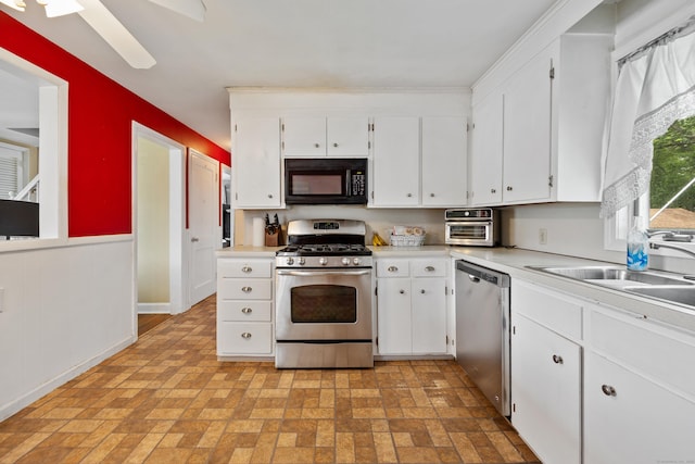 170 Celia Dr, Waterbury, CT 06705 - kitchen featuring appliances with stainless steel finishes, brick patterned flooring, light countertops, white cabinets, and a wainscoted wall