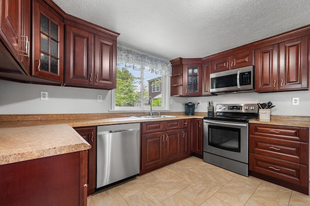 10 Harding Ave, Newington, CT 06111 - kitchen featuring stainless steel appliances, glass insert cabinets, light countertops, a textured ceiling, and light tile patterned floors