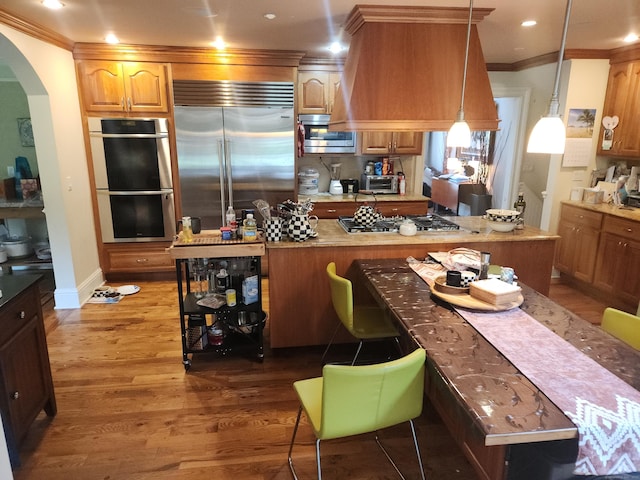 8 Caddy Rd, Norwalk, CT 06851 - kitchen featuring built in appliances, wood finished floors, arched walkways, crown molding, and custom exhaust hood