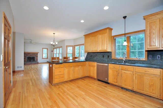 146 Pheasant Way S, Windsor, CT 06074 - kitchen featuring stainless steel dishwasher, light wood-style flooring, a peninsula, a brick fireplace, and decorative backsplash
