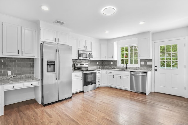 75 Beecher Ave, Shelton, CT 06484 - kitchen featuring appliances with stainless steel finishes, backsplash, white cabinetry, light stone countertops, and light wood-style flooring