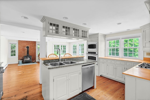795 Rte 148, Killingworth, CT 06419 - kitchen with stainless steel appliances, light wood-style flooring, a wood stove, a center island with sink, and glass insert cabinets