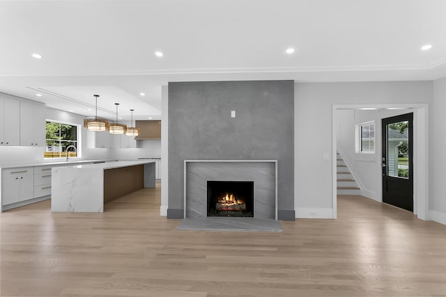 92 Westwood Rd, Fairfield, CT 06825 - unfurnished living room with light wood-style flooring, recessed lighting, a large fireplace, and stairs