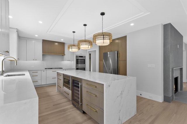 92 Westwood Rd, Fairfield, CT 06825 - kitchen featuring stainless steel appliances, beverage cooler, a large island, a tray ceiling, and light wood-type flooring