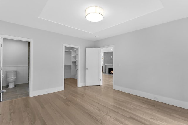 92 Westwood Rd, Fairfield, CT 06825 - unfurnished bedroom with wood finished floors, a spacious closet, ensuite bath, and a warm lit fireplace