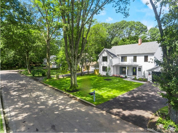 92 Westwood Rd, Fairfield, CT 06825 - view of front of property featuring a front lawn, a chimney, driveway, and stucco siding