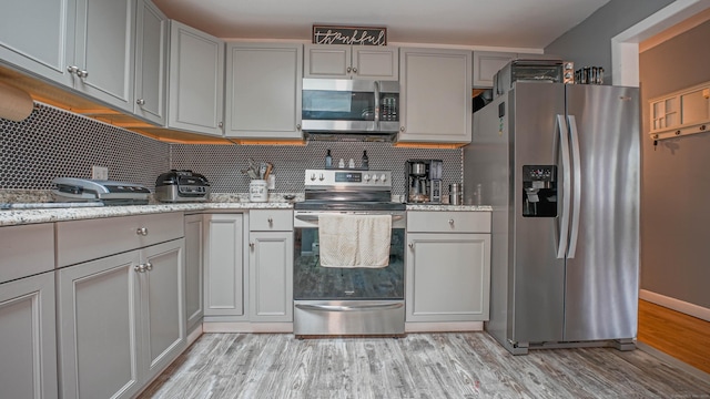 83 View Ter, East Haven, CT 06512 - kitchen with appliances with stainless steel finishes, gray cabinetry, light wood finished floors, backsplash, and light stone counters