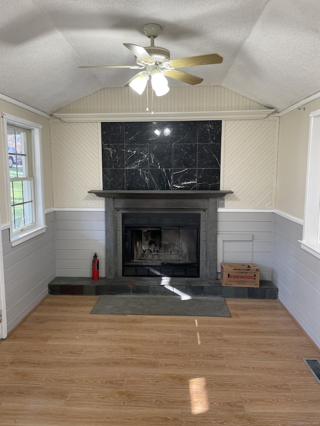 23 Merriman Ln, Prospect, CT 06712 - detailed view of a textured ceiling, a tile fireplace, wood finished floors, ceiling fan, and wainscoting